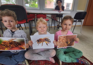 Dzieci pokazują ilustracje z pszczołami.