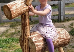 Dziewczynka siedzi na drewnianym koniku.