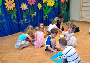 Dzieci w małych zespołach pracują nad wykonaniem plakatu.
