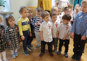 Grupa dzieci z najmłodszej grupy stoi ubrana są w galowe stroje