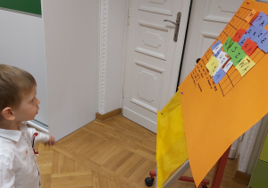 Chłopiec rozwiązuje na tablicy krzyżówkę o Polsce.