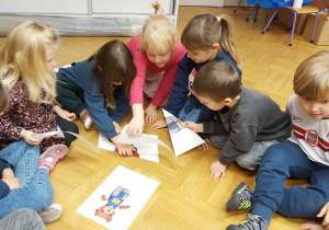 Dzieci siedząc na podłodze układają puzzle - Misia Uszatka.