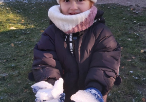 Dziewczynka pokazuje trzymane w rękach płaty lodu.