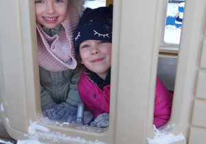 Dwie dziewczynki bawią soę w plastikowym domku - wyglądają przez okno.