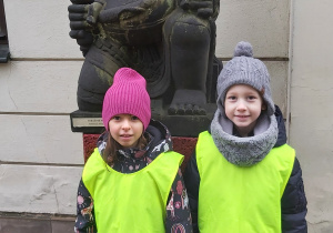 Dziewczynka i chłopiec stoją obok azjatyckiej rzeźby.