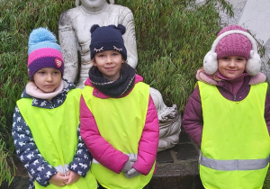 Trzy dziewczynki stoją obok azjatyckiej rzeźby.