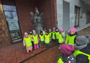 Grupa dzieci stoi obok azjatyckiej rzeźby przd wejściem do Muzeum Azji i Pacyfiku.