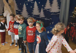 Dzieci tańczą w kole podczas zabawy z Mikołajem.