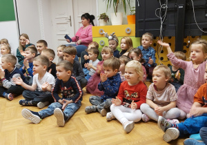 Dzieci siedzą na podłodze i oglądają przygotwany spektakl.