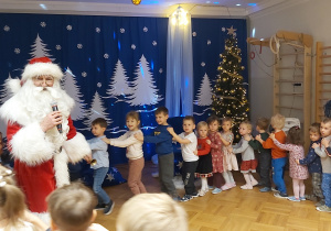 Dzieci tworzą "pociąg" za Mikołajem.