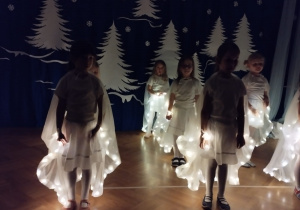 Dziewczynki tańczą w świecących pelerynach.