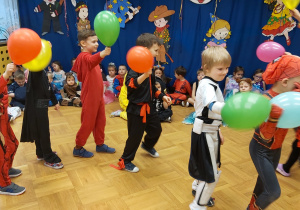 Dzieci tworzą taneczny korowód z balonami w ręku.