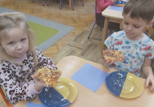 Dziewczynka i chłopiec jedzą pizzę.