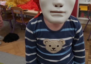 Chłopiec pozuje w białej masce na twarzy oraz w pirackiej chustce na głowie.