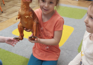Dziewcynka bawi się dinozaurem.