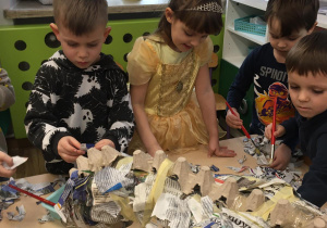 Dzieci wykonują sylwetę dinozaura z gazet.