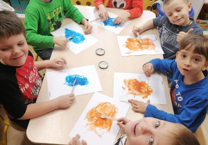 Dzieci rysują wzory plastikowym widelcem w plamie z farby.