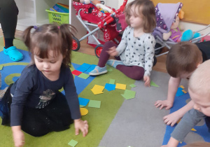 Dzieci segregują rozłożone na dywanie figury wg podanej cechy.