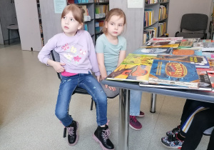 Dzieci siedzą przy stolikach w szkolnej bibliotece.