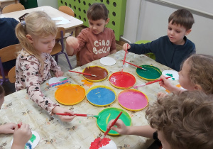 Dzieci malują farbami wycięte z papieru koła. Tworzą w ten sposób planety wg własnego pomysłu.