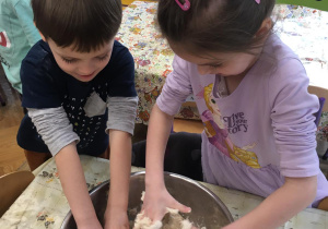 Dziewczynka i chłopiec przygotowują w matalowej, srebrnej misce masę solną..