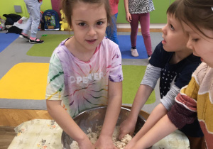 Dzieci przygotowują w matalowej, srebrnej misce masę solną - wygniatają masę.