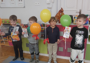 Grupa chłopców prezentuje otrzymane od koleżanek zakładki oraz balony.