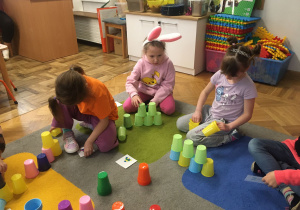 Dzieci układają wieżę z kolorowych kubków wg ustalonego kodu.