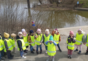 Grupa dzieci stoi z Marzanną na tle Wisły.