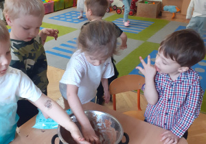 Dzieci z maluszków wylizują z garnka czekoladę.