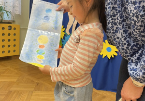Dziewczynka prezentuje własnorcznie wykonany rysunek - "Układ Słoneczny" i opowiada o nim.