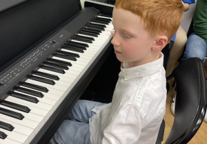Chłopiec gra na pianinie.