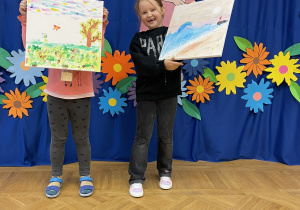 Dwie dziewczynki pokazują wykonane podczas uroczystości malunki