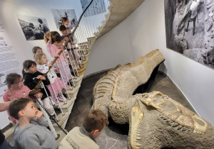 Dzieci oglądają odkopane kości dinozaura.
