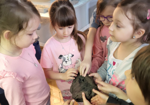 Dziewczynki trzymają w ręku i oglądają jeden z eksponatów- minerał.
