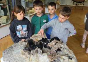 Dzieci oglądają jeden z eksponatów- minerał.