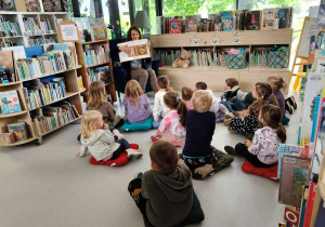 Dzieci słuchają bajki czytanej przez panią bibliotekarkę.