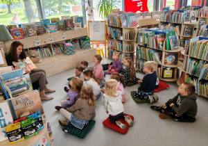 Dzieci słuchają bajki czytanej przez panią bibliotekarkę.