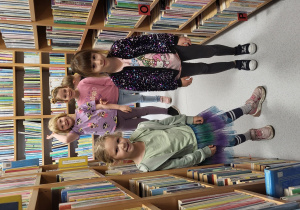 Dzieci spacerują pomiędzy bibliotecznymi półkami.