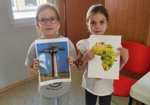 Dziewczynki prezentują ilustracje przedstawiające mapę Afryki oraz baobab