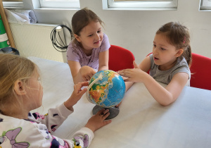 Trzy dziewczynki oglądają globus.