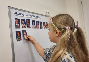 Dziewczynka zaznacza na tablicy swoją obecność w przedszkolu.
