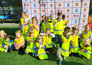 Dzieci pozują do zdjęcia grupowego z otrzymanymi medalami.