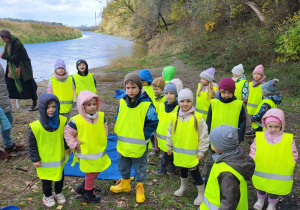 Grupa dzieci stoi nad rzeką.