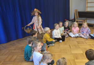 Dzieci z grupy 5 i 6 latków siedzą w kole i śpiewają piosenkę o darach Pani Jesieni. Jedna z dziewczynek w stroju Pani Jesieni chodzi dookoła dzieci i rozdaje im jesienne dary.