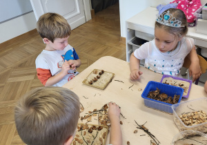Dwoje dzieci zatapia łupinki w podłożu z gipsu.
