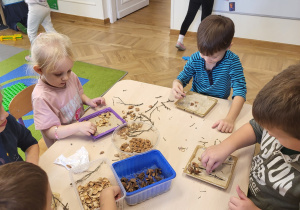 Dzieci układają wzory z pestek ze śliwek.