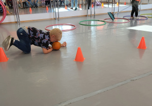 Chłopiec pokonuje tor przeszkód turlając dynię głową.