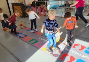 Dzieci przeskakują wg namalowanych śladów stóp.