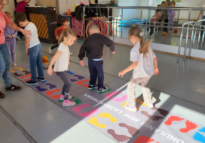 Dzieci przeskakują wg namalowanych śladów stóp.